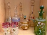 de nombreuses bouteilles et verres en verre de différentes couleurs sur une étagère
