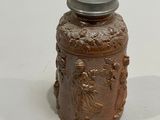 a small brown jar with a lid on a white surface