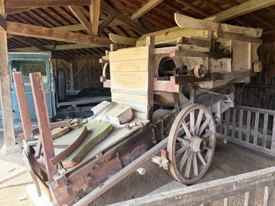 un vieux chariot en bois muni d'un siège en bois, dans une grange