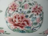 a white vase with pink flowers on it sitting on a table