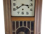 une image représentant une horloge en bois posée sur un mur blanc