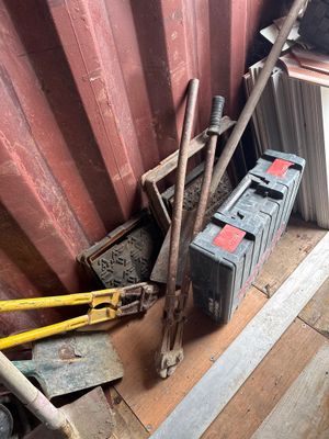 un tas d'outils posé par terre près d'un mur rouge
