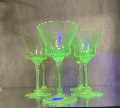 trois verres à vin verts posés sur une table en verre