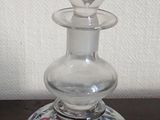 un petit vase en verre muni d'un couvercle en verre, posé sur une table