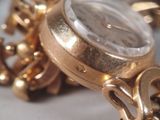 a close up of a gold watch with a chain around it