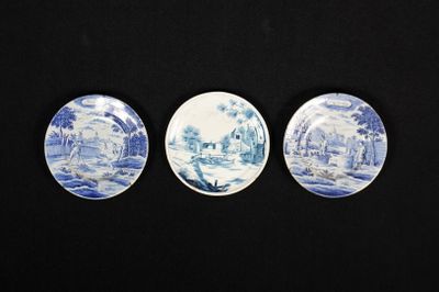 trois assiettes bleues et blanches posées sur une surface noire, sur fond noir