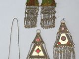 trois paires de boucles d'oreilles et un collier posés sur un fond blanc