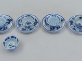 six tasses à thé et soucoupes bleues et blanches posées sur une table