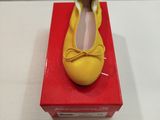 une chaussure jaune posée sur une boîte rouge