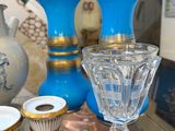 une table en verre sur laquelle sont disposés des vases bleus et d'autres objets décoratifs