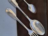 three silver spoons and two silver spoons on a brown napkin