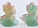 two green and pink leaf shaped vases on a white surface