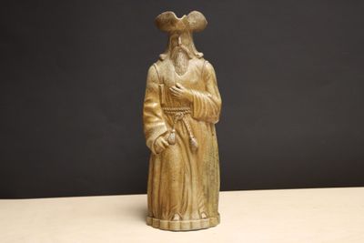 une vieille statue représentant un homme barbu coiffé d'un chapeau