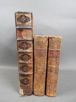 three old books are stacked on top of each other on a table