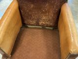 an old brown leather chair sitting in a room next to a dresser