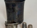 une tasse en argent et un dé à coudre posés sur une table