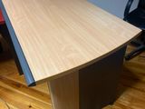 a wooden desk with a black chair in the corner