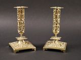 paire de bougeoirs anciens en laiton sur un socle, sur fond noir