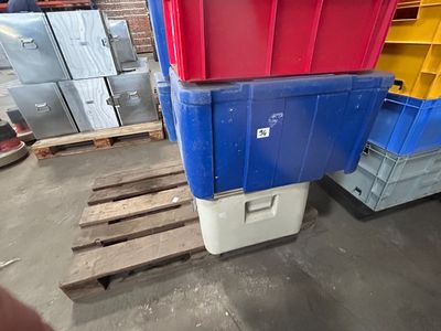 une pile de bacs en plastique posée sur une palette dans un entrepôt