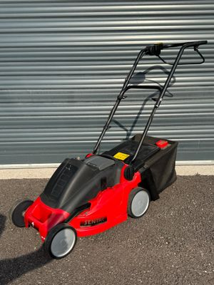 une photo d'une tondeuse à gazon rouge garée devant la porte d'un garage
