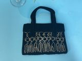 black velvet handbag with gold beading and a glass of water
