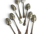 six silver spoons are arranged in a circle on a white surface