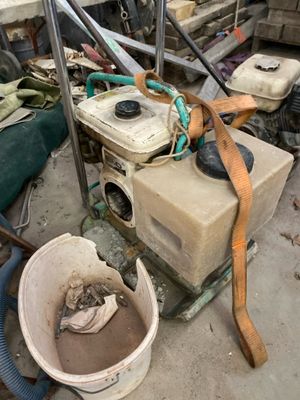 a pile of junk in a garage with a bucket and a hose