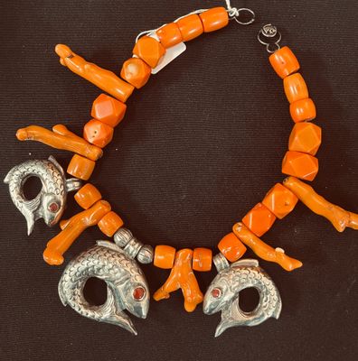un bracelet orange orné de perles argentées et de corail sur fond noir