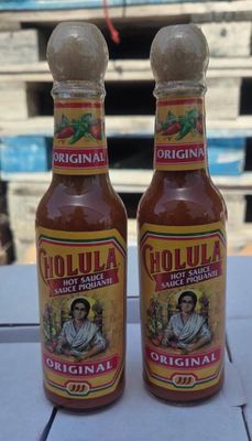 two bottles of hot sauce sitting on top of a table