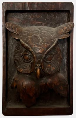 a wooden plaque with an owl on it ' s face