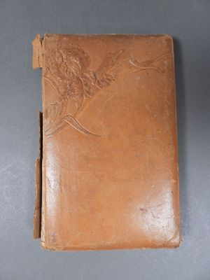 an old leather book with a bird design on the cover