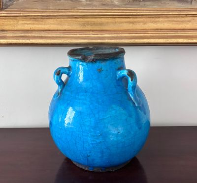 un vase bleu posé sur une table devant un tableau