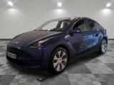 La Tesla Model Y bleue est garée dans une pièce dont le sol est en damier.