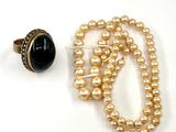 un collier de perles et une bague posés sur un fond blanc