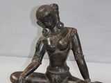 statue of a woman sitting in a lotus position on a white surface