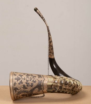an old horn with a chain attached to it sitting on a table