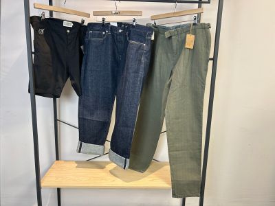 trois paires de jeans pour homme suspendues à un portant dans un magasin de vêtements