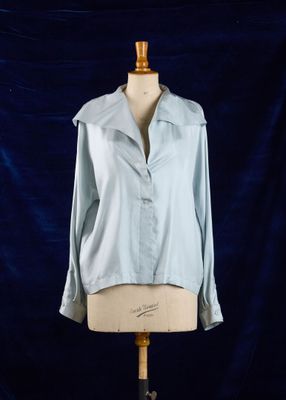 une chemise bleue posée sur un mannequin, devant un fond bleu