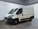 La camionnette blanche est garée dans une grande pièce au sol gris.