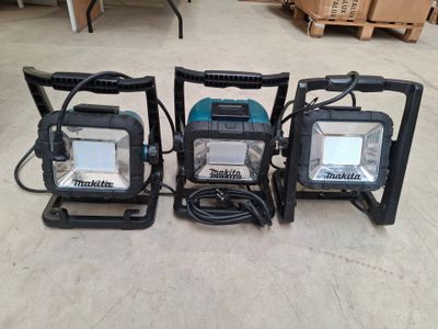 three portable work lights are sitting on the floor in a warehouse