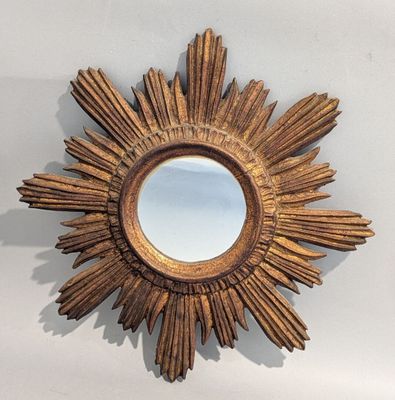 un miroir doré à rayons solaires accroché au mur