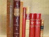 Plusieurs vieux livres sont empilés les uns à côté des autres sur une étagère.