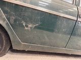 a green car that has been damaged and is sitting in the garage