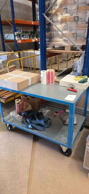 un chariot bleu chargé de cartons dans un entrepôt