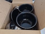 a cardboard box filled with black bowls and spoons