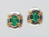 une photo d'une paire de boucles d'oreilles émeraude posées sur une surface blanche