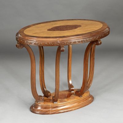 une image représentant une table en bois au plateau sculpté, sur fond gris