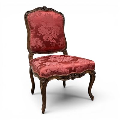une chaise rouge dont le dossier est recouvert d'un tissu à motifs floraux et dont la structure est en bois