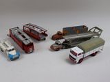 Plusieurs camions miniatures et camions sont alignés sur une surface blanche