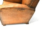 a brown leather chair that is sitting on a white surface